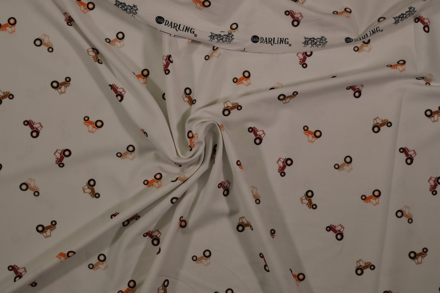 Ecrufarbener Baumwolljersey mit kleinen Traktoren – Detailaufnahme der Stoffstruktur