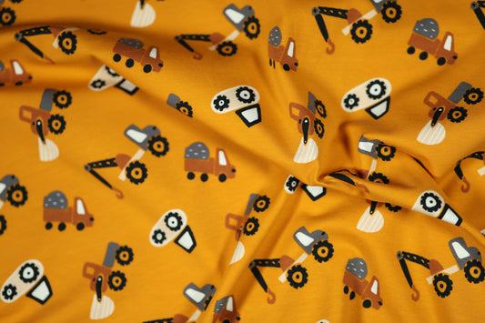 Senfgelber Baumwollstoff mit einem Muster aus Baggern und Lastwagen