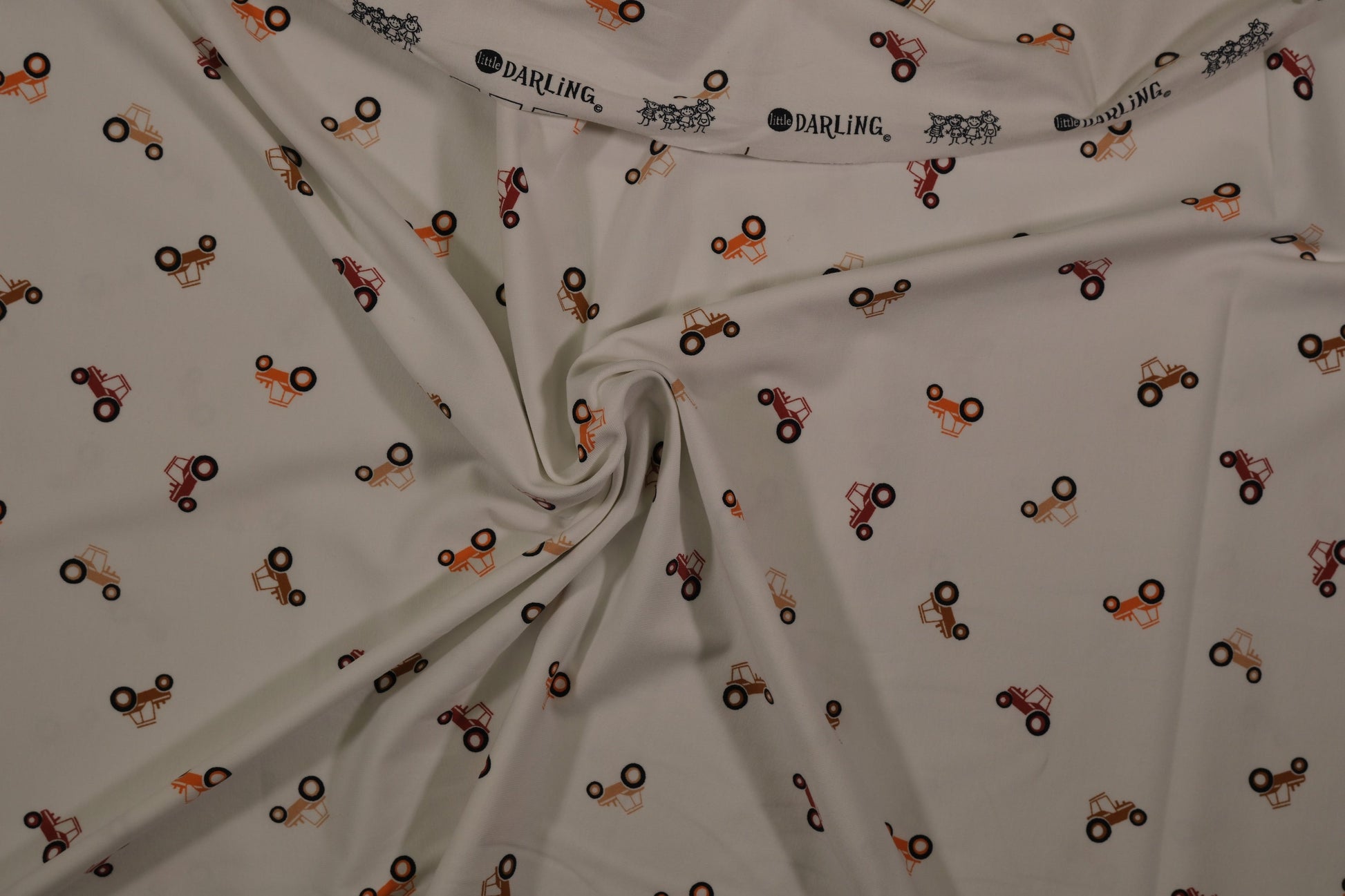 Ecrufarbener Baumwolljersey mit kleinen Traktoren – Detailaufnahme der Stoffstruktur