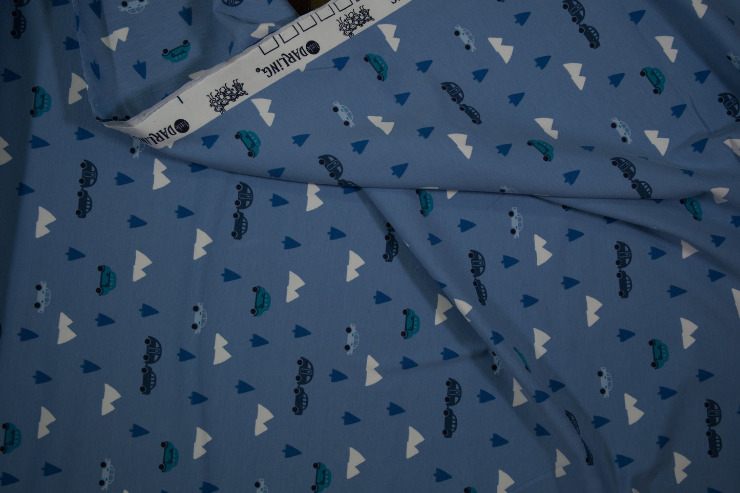 Blauer Baumwolljersey mit Autos, Bäumen und Bergen – Detailaufnahme der Stoffstruktur