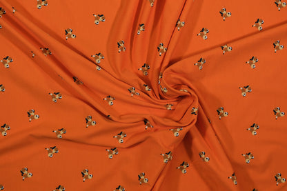 Oranger Baumwolljersey mit kleinen Hundemotiven – Detailaufnahme der Stoffstruktur