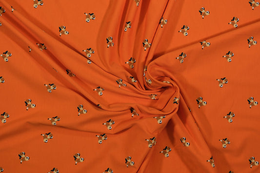Oranger Baumwolljersey mit kleinen Hundemotiven – Detailaufnahme der Stoffstruktur