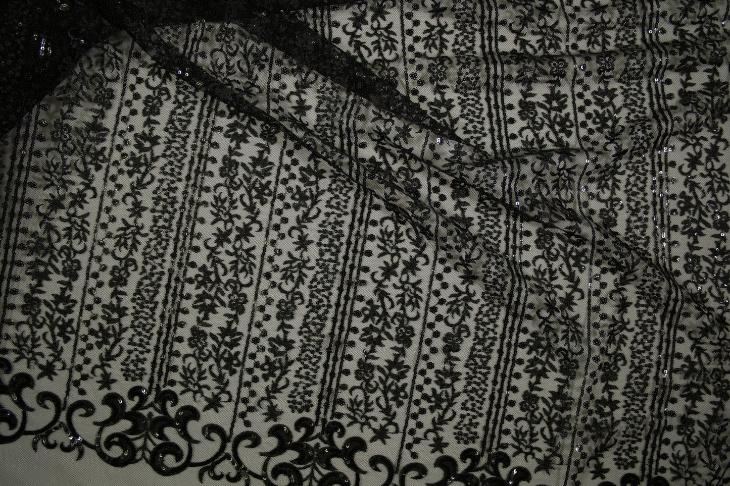 Schwarze Spitzenware auf Tüll mit floralen Streifen und Pailletten in Nahaufnahme
