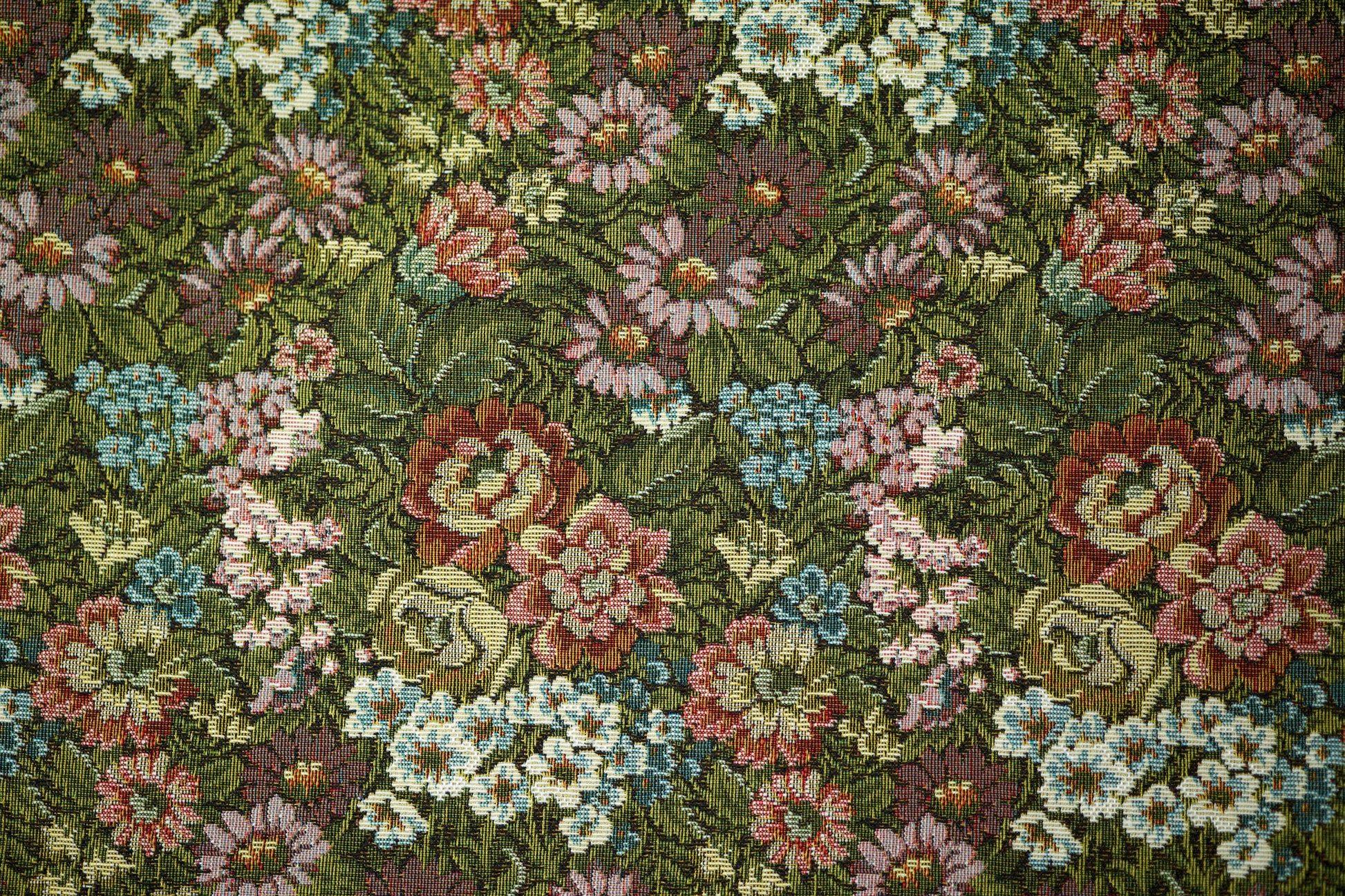 Bunter Möbelstoff mit Wiesenblumenmuster auf dunkelgrünem Grund – perfekt für rustikale und verspielte Einrichtungen