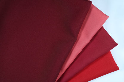 Polyester Panama Stoffe in Rot- und Violetttönen – nebeneinandergelegt von Weinrot über Hellrot bis hin zu strukturiertem Rot für elegante Farbvergleiche bei Dekostoffen