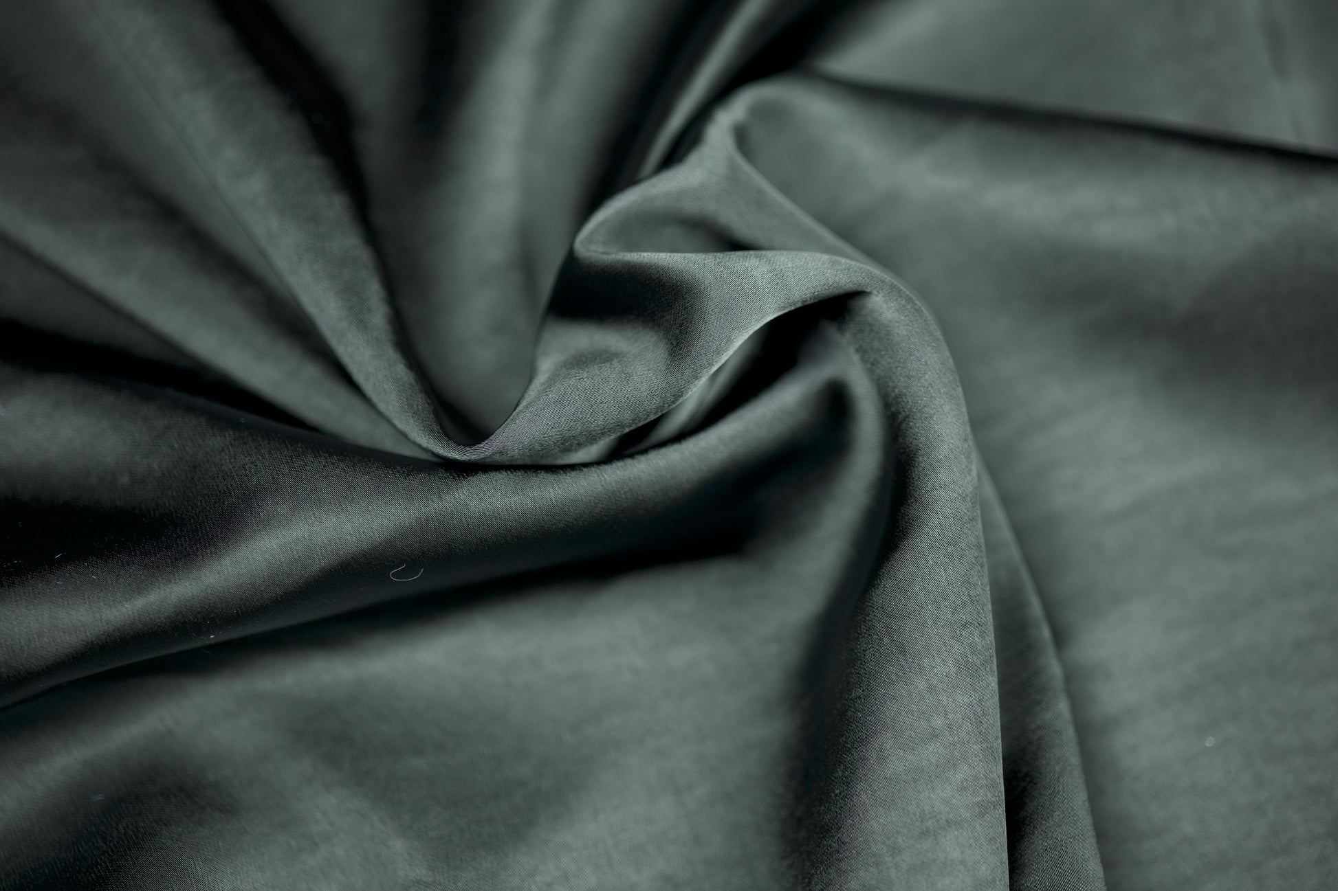 Nahaufnahme eines luxuriösen Satinstoffs in dunklem Schiefergrau mit elegantem Glanz und natürlichem Faltenwurf – ideal für stilvolle Nähprojekte